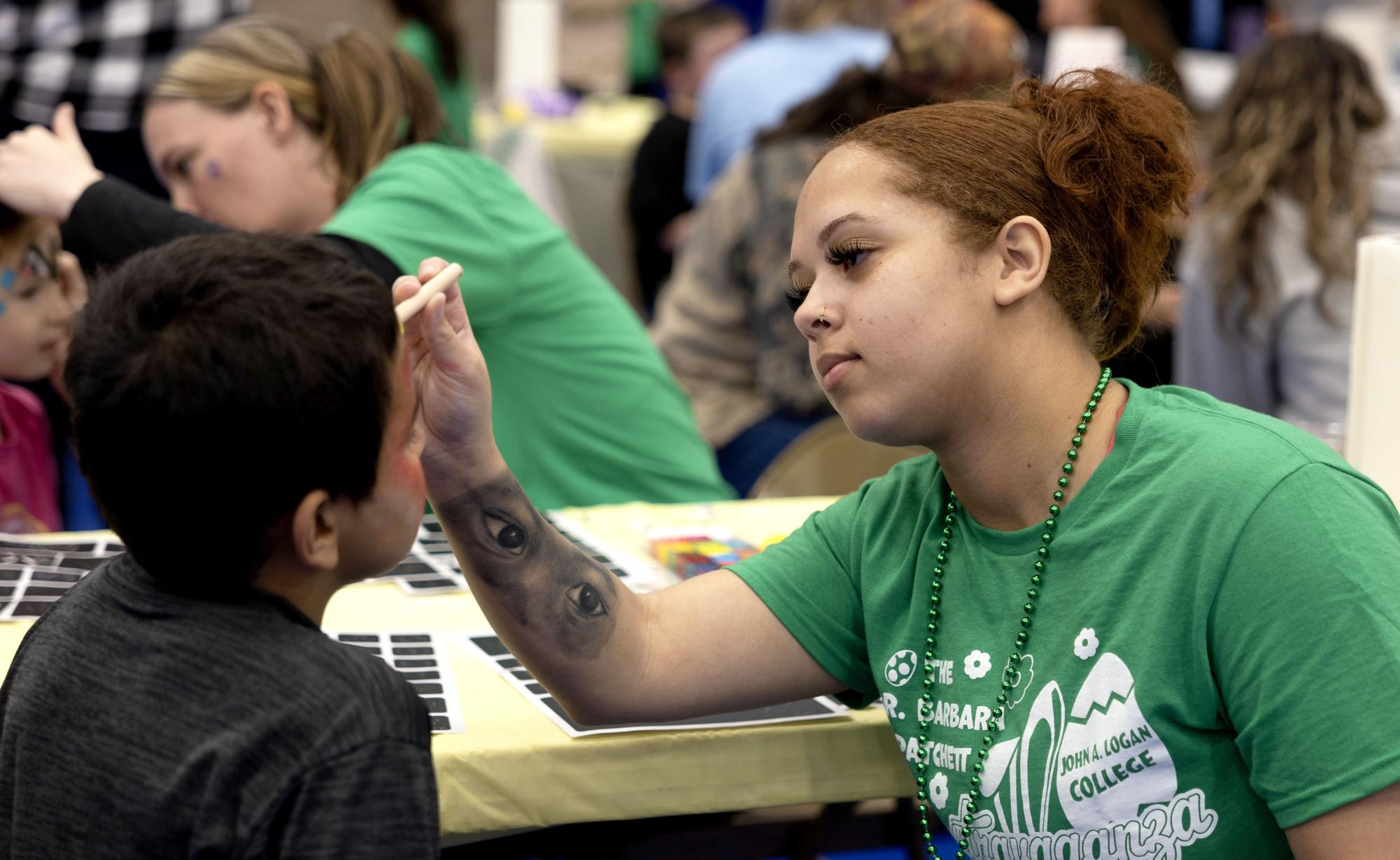 Daishen Williams paints the face of a young boy during the Dr. Patchett Eggstravaganza April 5.