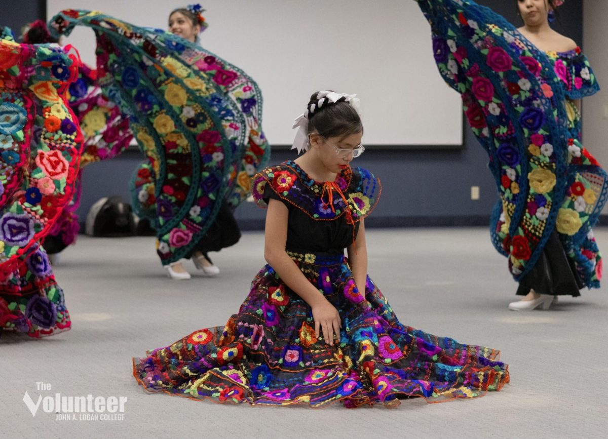 A dancer from the Cobden High School ESL team kneels during a traditional performance at World Music and Food Day.